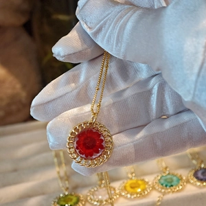 Close-up of handmade gold necklace with a real red dried flower in a round pendant