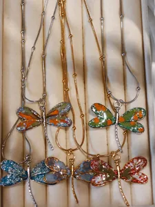 Detailed view of colorful dragonfly pendants with floral texture in a jewelry box