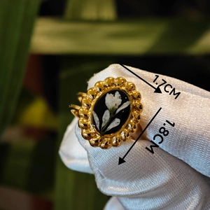 Detail shot of vintage gold ring with white dried flower on black oval setting