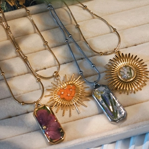 Detail view of handmade stainless steel necklaces with real dried flowers in resin charms