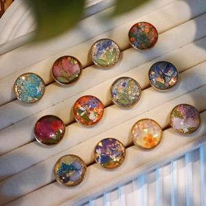 Close-up of handmade resin rings with real dried flowers and gold metal edges