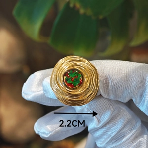 Dettaglio di un anello vintage dorato da 2,2 cm con intarsio floreale tenuto in guanti bianchi