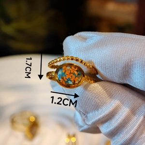 Detailed macro view of gold bead ring with orange dried flower and resin oval surface