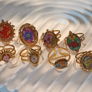 Macro view of handmade stainless steel rings with real dried flowers in resin