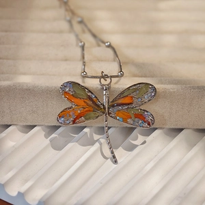 Macro detail of handmade dragonfly pendant featuring real dried flowers and resin