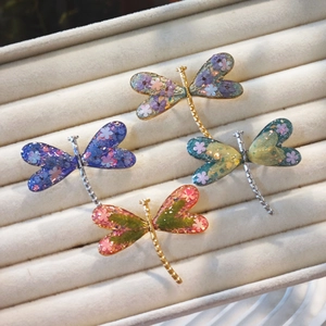 Detailed macro view of four colorful dragonfly rings with sparkling dried flower wings
