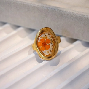Macro detail of handmade stainless steel ring with dried flowers in oval resin inlay