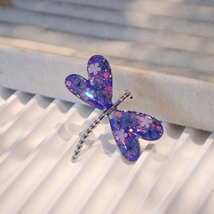 Macro detail of silver dragonfly ring with purple dried flowers and glitter in wings