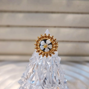 Detail of vintage gold ring with white flower center and sunburst texture