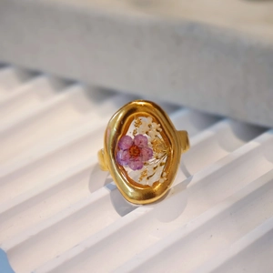 Macro shot of handmade gold ring featuring real purple dried flowers in resin inlay
