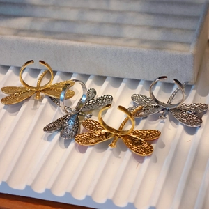 Detail of adjustable dragonfly rings with textured wings in gold and silver finish