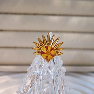 Macro detail of sunburst stainless steel ring with red dried flower center on crystal stand