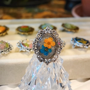 Detail of vintage silver lace ring featuring real orange and blue dried flowers in resin