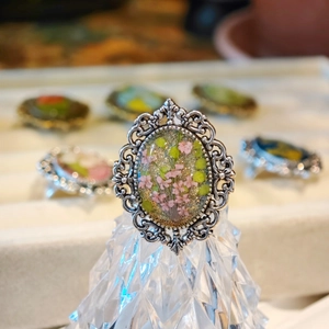 Detailed macro of vintage silver lace ring with pink dried flowers and embossed metal frame