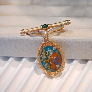 Detail of vintage gold brooch with blue flower specimen and green gemstone inlay