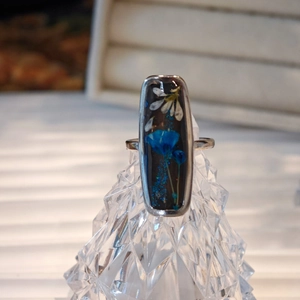 Detail view of handmade resin ring with real dried flowers and ink-style art accents