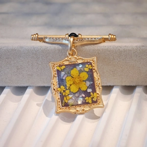 Detail of vintage gold flower brooch with dried yellow bloom and embossed frame