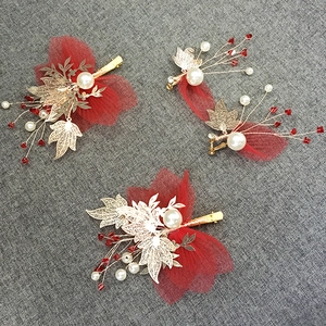 Detail of red pleated tulle hair clips and earrings set with gold leaf and pearls