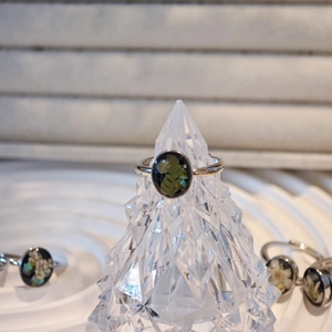 Close-up of handmade silver open ring with black resin and green leaf inlay detail