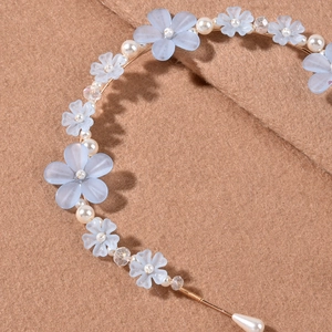 Detailansicht von hellblauer mattierter Blume und weißer Kunstperle am Stirnband