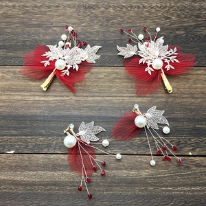 Detail of red bridal hair clips and earrings set with pearls and mesh tulle