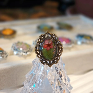 Detail of vintage bronze ring with red dried flowers under transparent resin surface