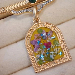 Detail of arch-shaped gold brooch with dried flowers and intricate scroll engraving