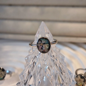 Macro shot of silver ring with oval black inlay and delicate dried flower resin art
