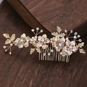 Close-up of golden bridal hair comb with elegant alloy flowers, pearls and rhinestones