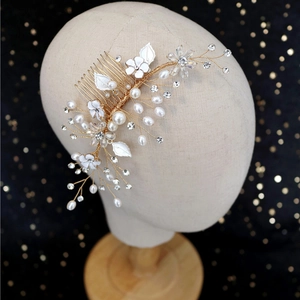 Handmade bridal hair comb with gold leaves, white enamel flowers and pearls on black background