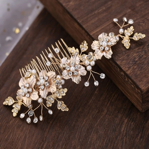 Close-up of golden bridal hair comb with white pearls, rhinestones and leaf details