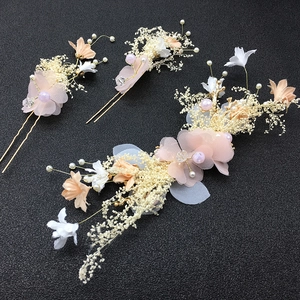 Bridal hair accessory set with pink floral petals, white pearls and gold wire on black background