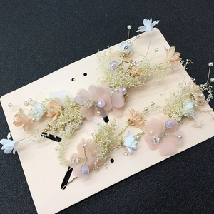 Detailed view of pink fabric flowers and white faux pearls on gold bridal hair pins