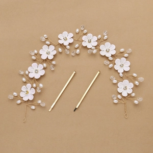 Detail eines handgefertigten Brautstirnbands mit weißen Stoffblumen, Perlen und Goldnadeln