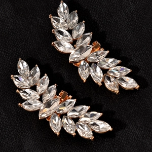 Close-up of golden leaf ear crawlers with marquise rhinestones on black fabric