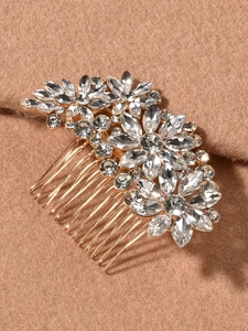 Close-up of golden crystal flower hair comb with rhinestones on beige fabric background