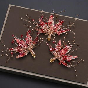 Detalle de tres pinzas para el cabello de hoja de arce con cristales rojos y perlas doradas
