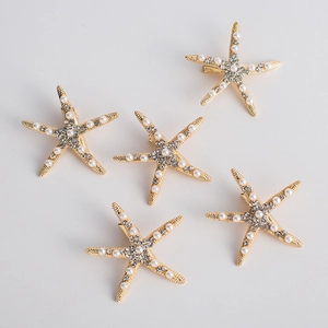 Five-piece golden starfish hair clips set with pearls and rhinestones on grey background