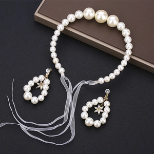 Detailed macro of white pearl accessory set with organza ribbon and floral earrings