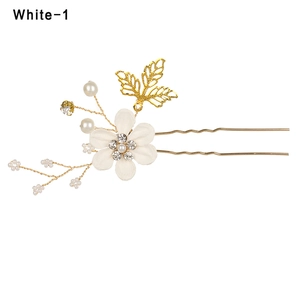 Detailed shot of handmade hair comb featuring white fabric flower and gold leaf accents