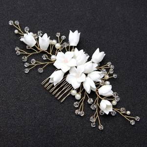 Dettaglio di fiori in ceramica bianca e perle su un pettine da sposa dorato
