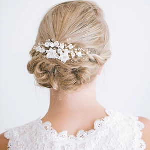 Dettaglio di un pettine da sposa con fiori in ceramica bianca, perle e cristalli