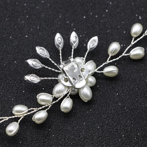 Dettaglio macro della clip per scarpe da sposa con perle e strass su sfondo nero