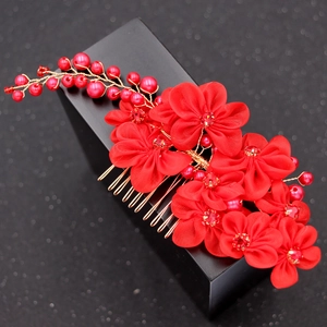 Macro view of handmade red bridal hair comb with fabric flowers and pearls