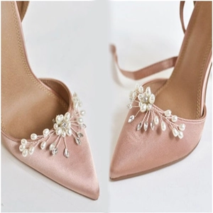 Dettaglio dei fermagli per scarpe con perle e strass su tacchi a spillo in raso rosa