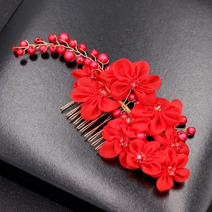 Macro shot of handmade red silk flowers on golden hair comb with red pearls