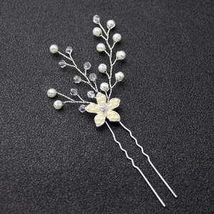 Détail d'une épingle à cheveux argentée avec fleur crème, perles et cristaux