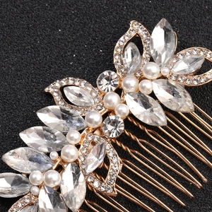 Détail d'un peigne à cheveux de mariée doré avec strass marquise et perles blanches