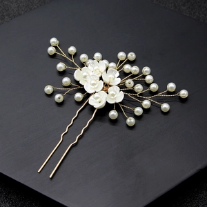 Close-up of handmade bridal U-shaped hair pin with pearls and white resin flowers