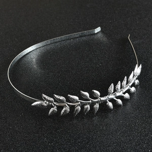 Detail of silver laurel leaf headband with intricate metal textures on black glitter